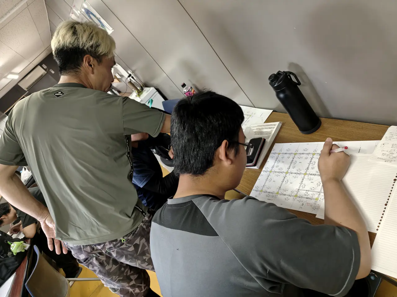 先輩の横で図面を読む若手
