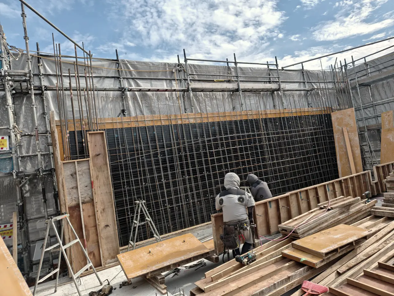 防寒着で型枠を建てる冬の現場
